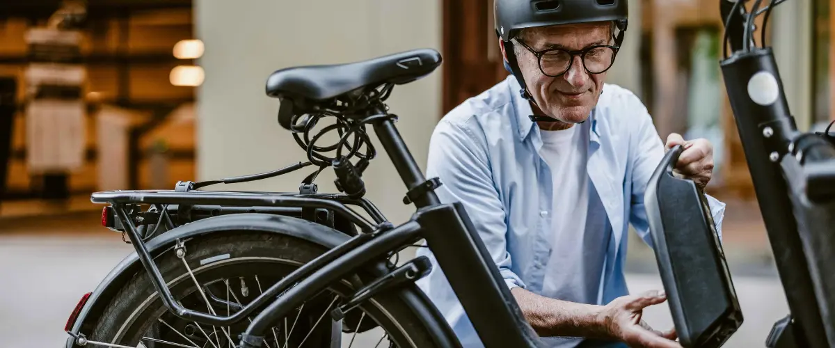 homme qui enlève sa batterie de vélo électrique (VAE)