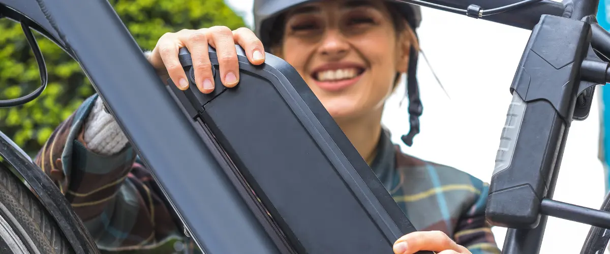 femme qui enlève la batterie de son vélo à assistance électrique